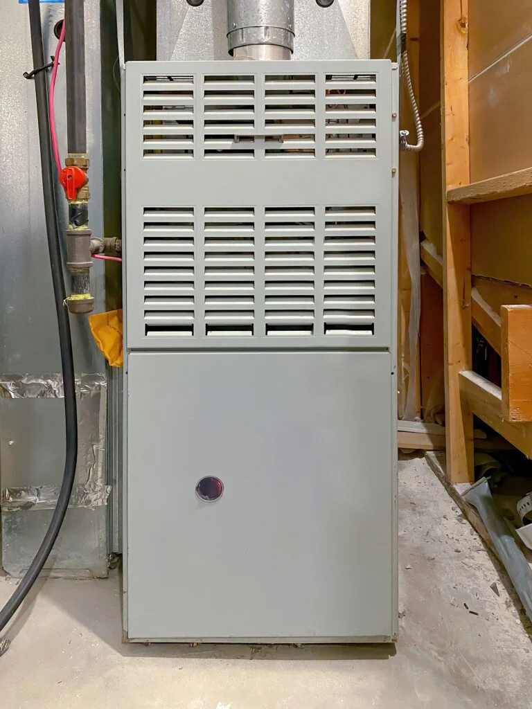 A tall, gray residential furnace with vented panels on top