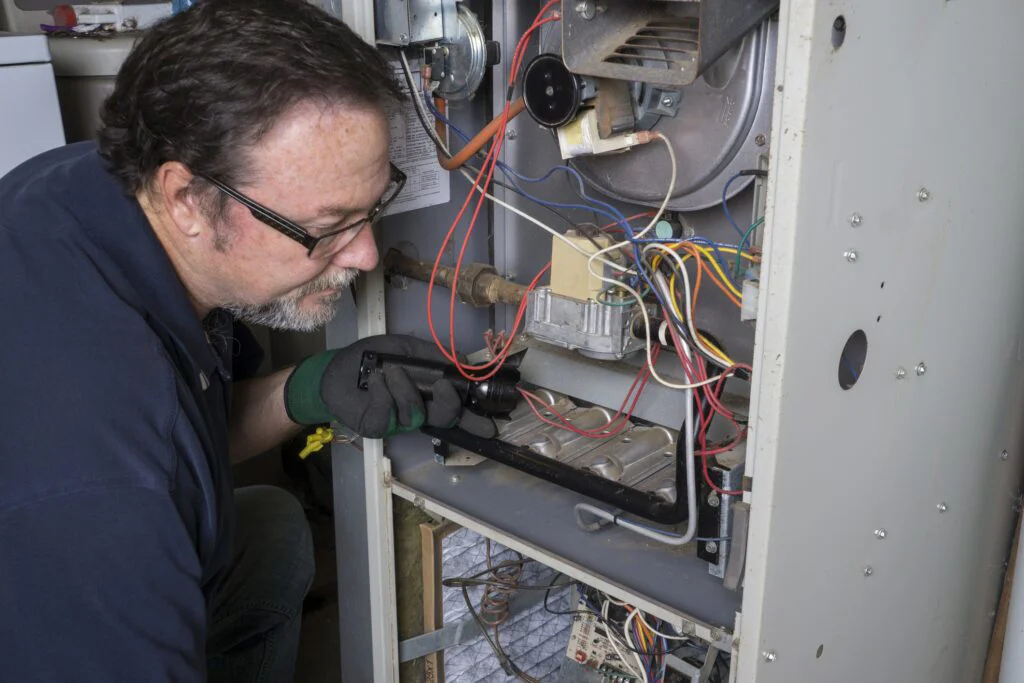 Technician inspecting a furnace's wiring