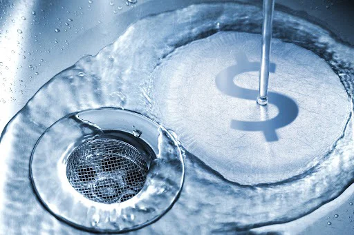 Water running down sink drain with dollar sign reflection